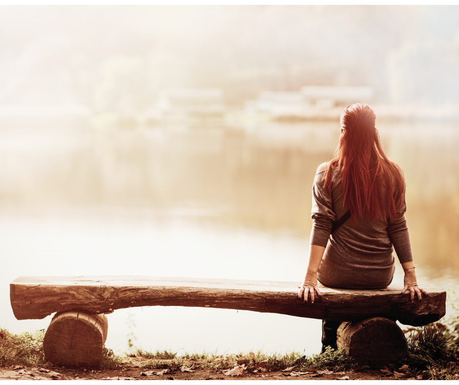 Woman sitting alone by a lake reflecting on why therapy hasn’t worked and feeling emotionally stuck despite personal development